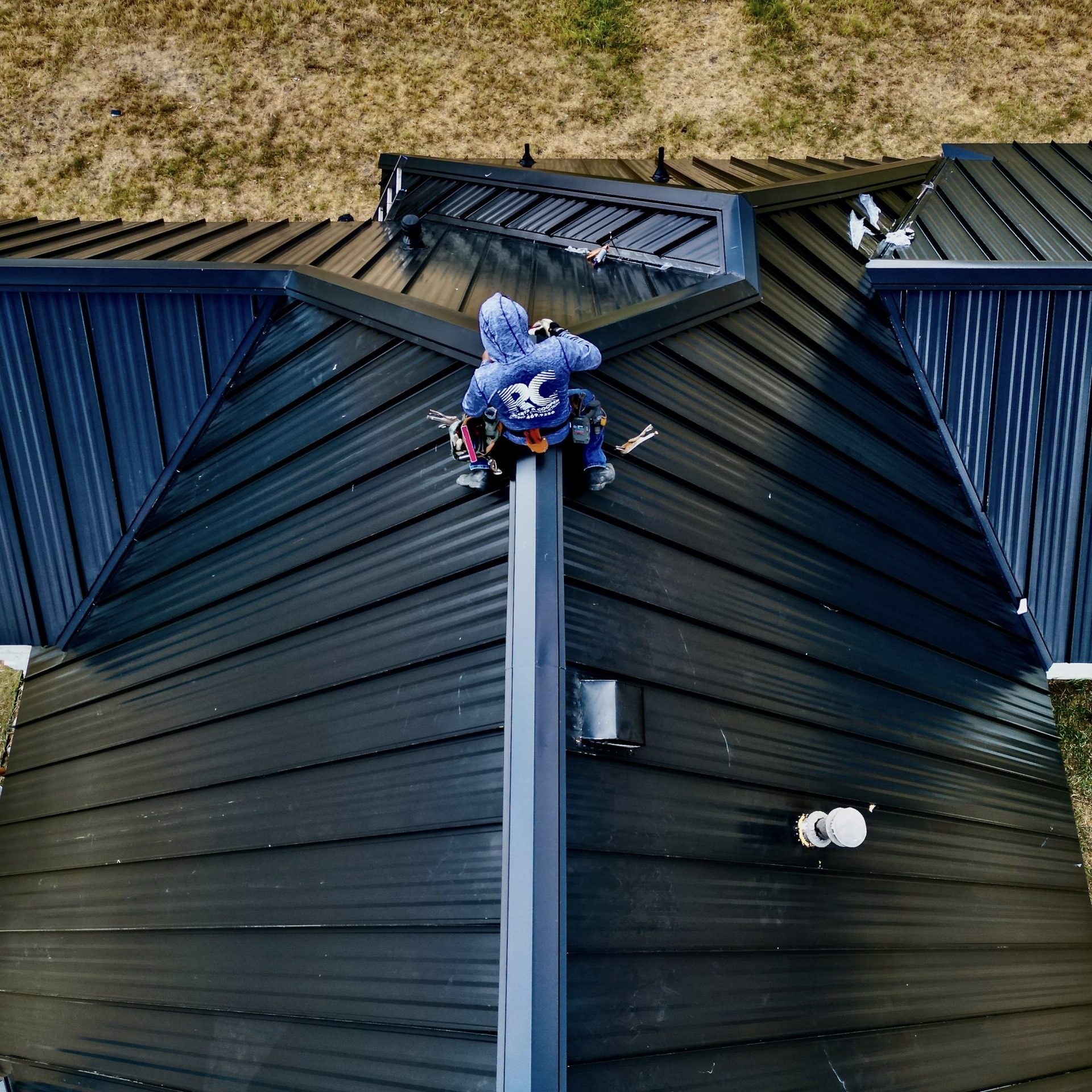 A man is installing a metal roof onto a home.